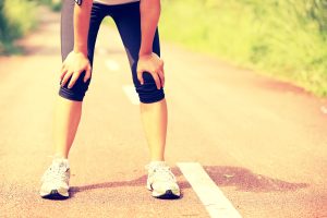 Femme essoufflée après avoir repris le running, attentive à une douleur musculaire dans la jambe