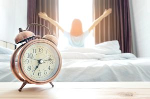 Une personne ouvre les rideaux au réveil pour retrouver un rythme de sommeil régulier après les vacances